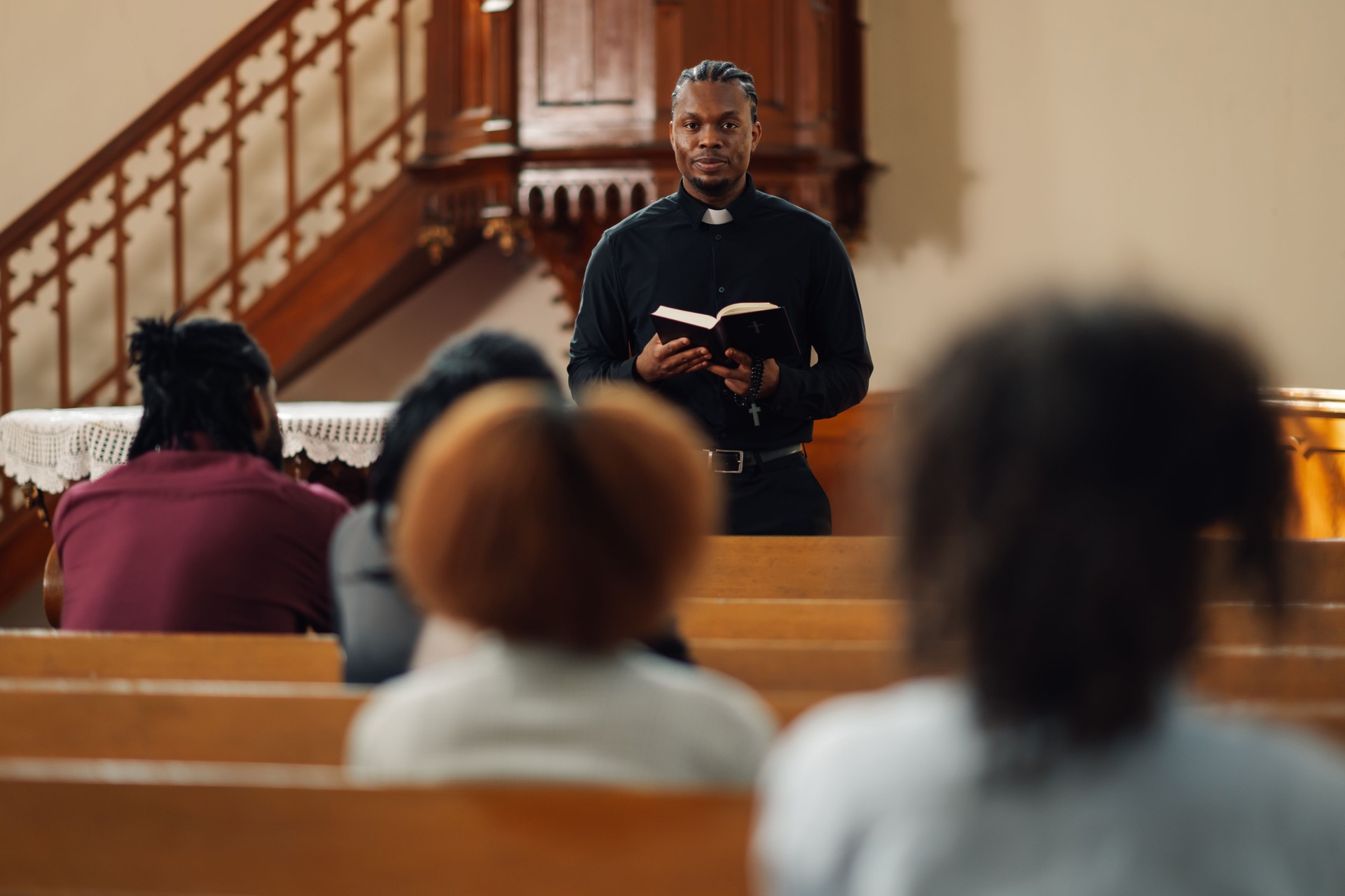Young priest holding bible speaking to congregation in church